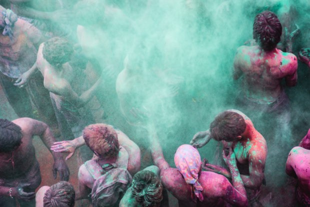 Man Tossing Colored Powder Into The Air During The Holi Festival In Puhskar India
