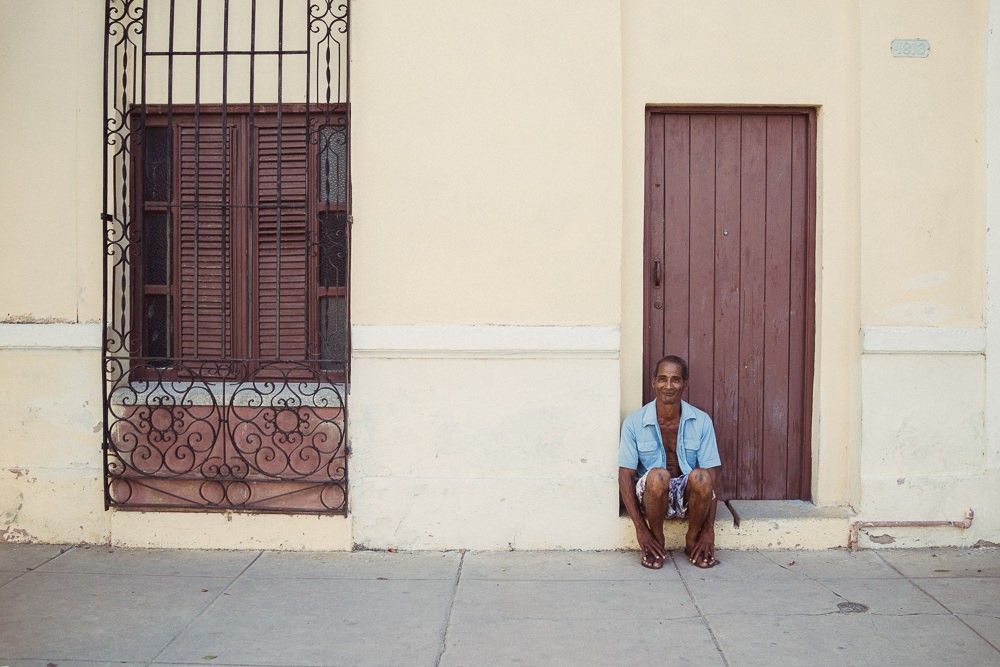 Portrait of Cuban man sitting on street smiling in Cienfuegos