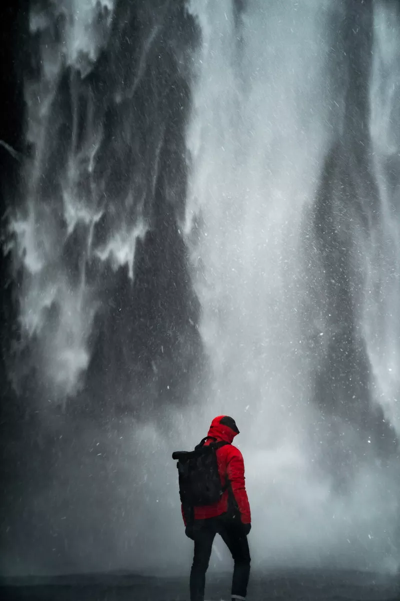 Man standing in front of Skogafoss waterfall