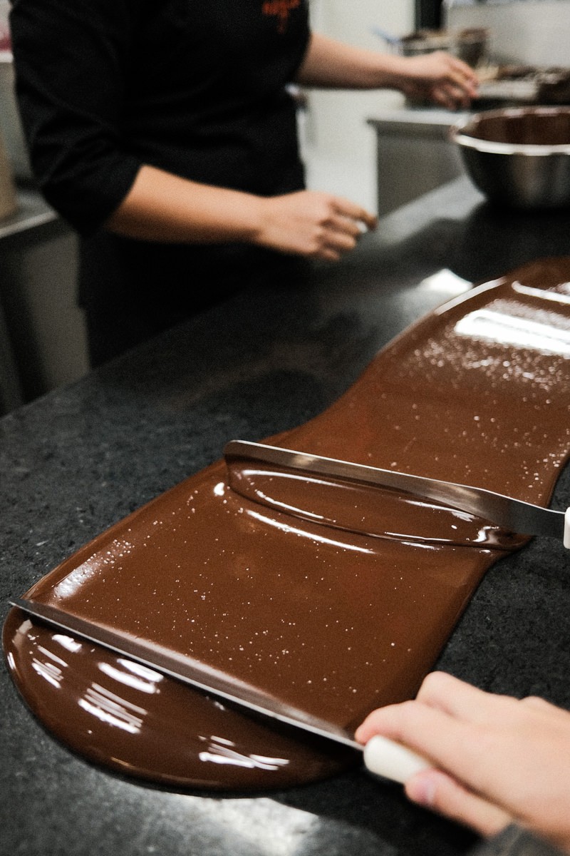 Woman spreading chocolate to be cooled for tempering