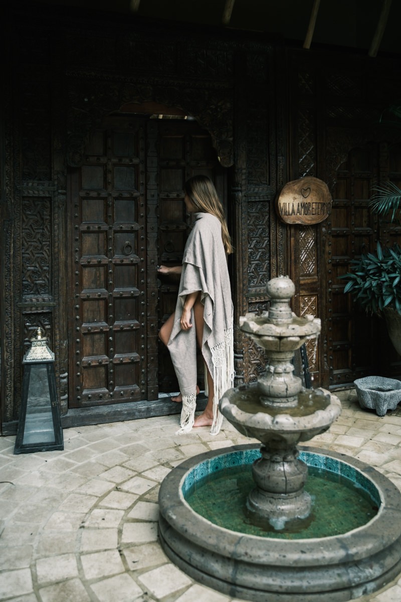 Woman entering wooden gated door of Amor Eterno Villa in Sayulita