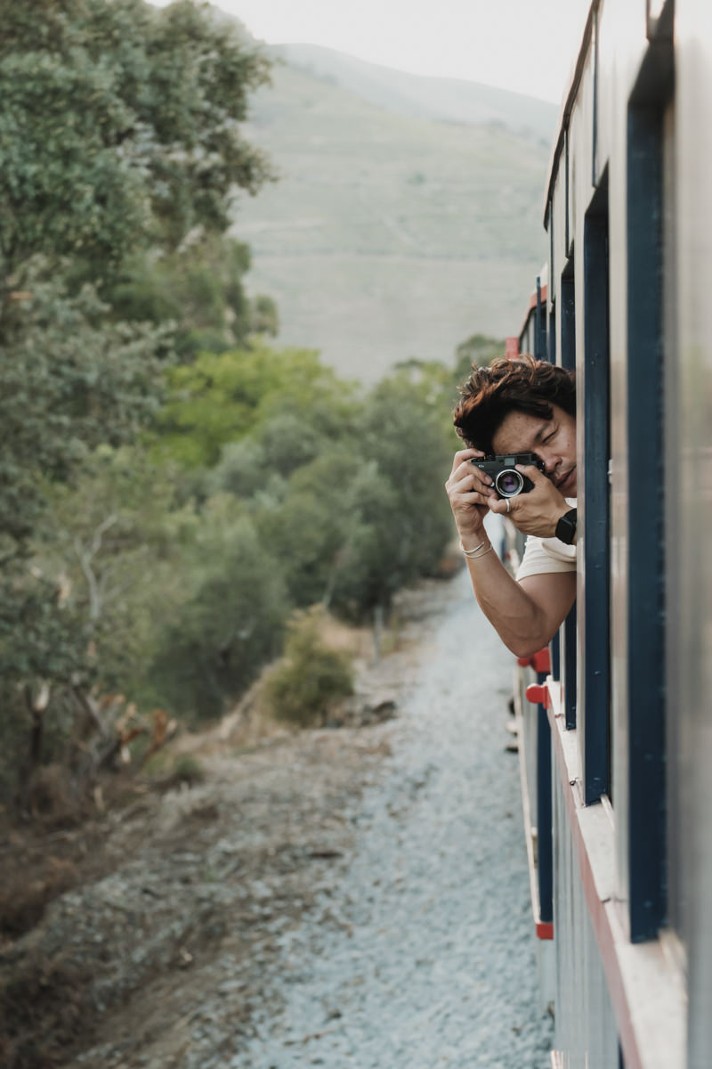 man taking photograph outside window of train in the duoro valley