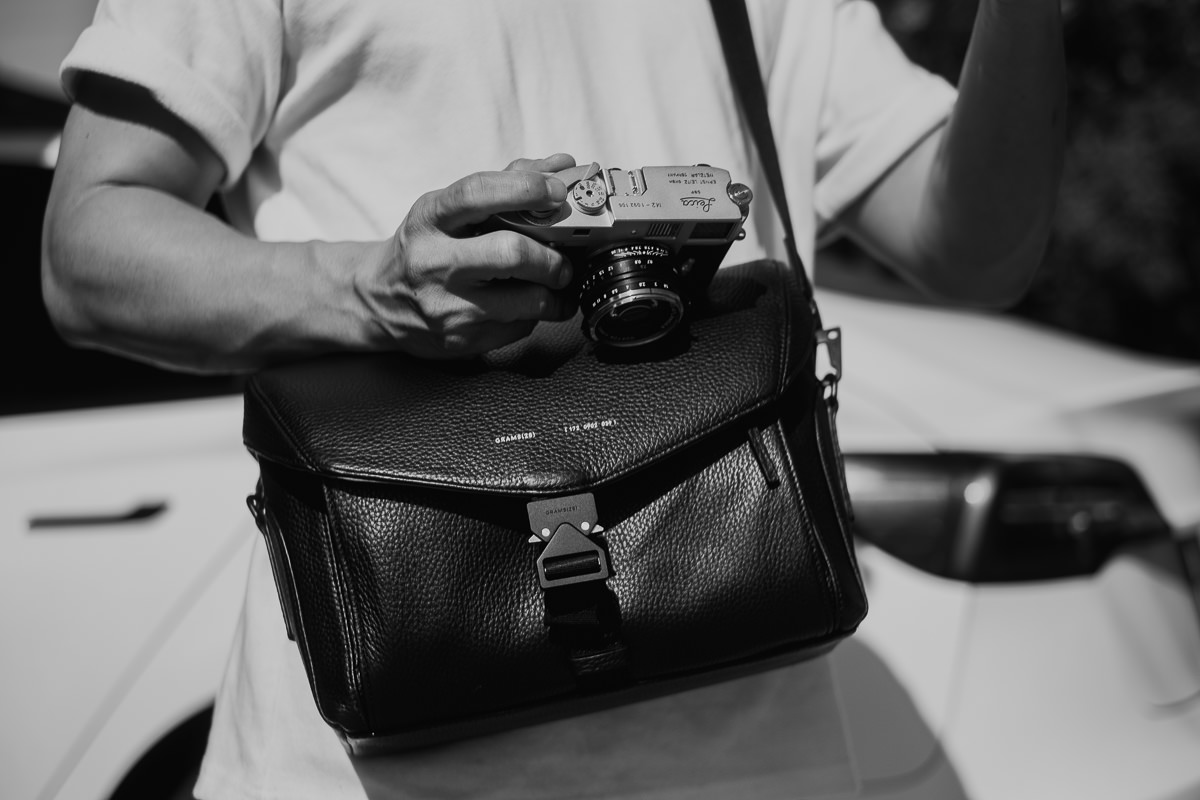 Black and white photo of man wearing Grams28 172 Camera Sling Bag
