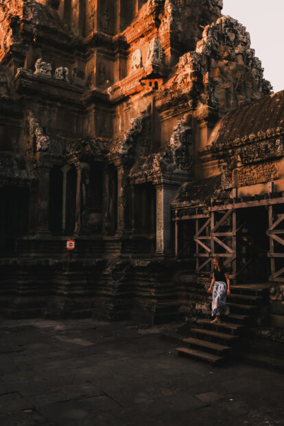 Woman walking inside Angkor wat at sunrise