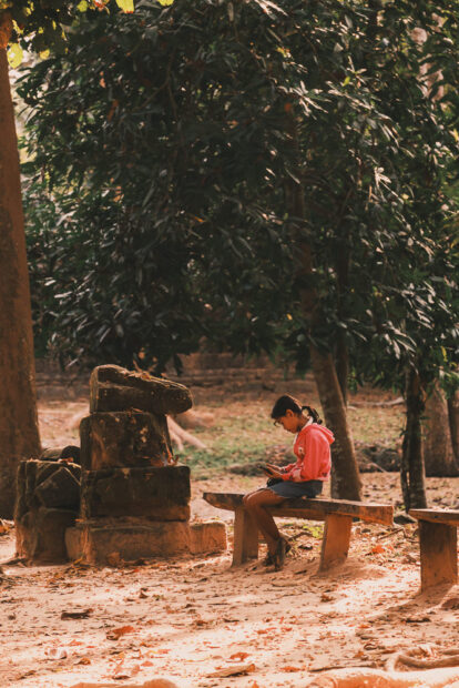 Girl sitting on a bench at Ta Som