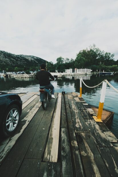 Car and man on motorbike on the cable ferry at Butrint
