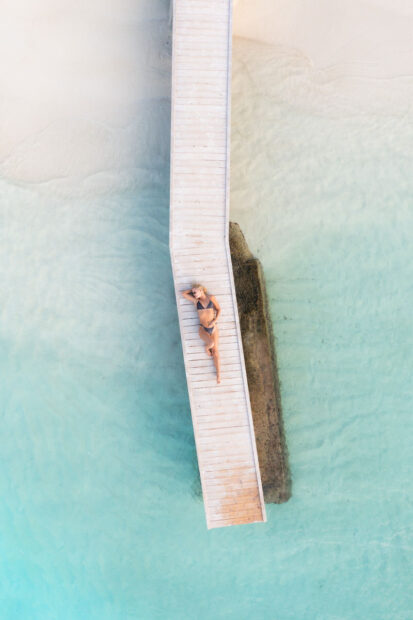 Ksamil beach from drone with girl laying on the pier