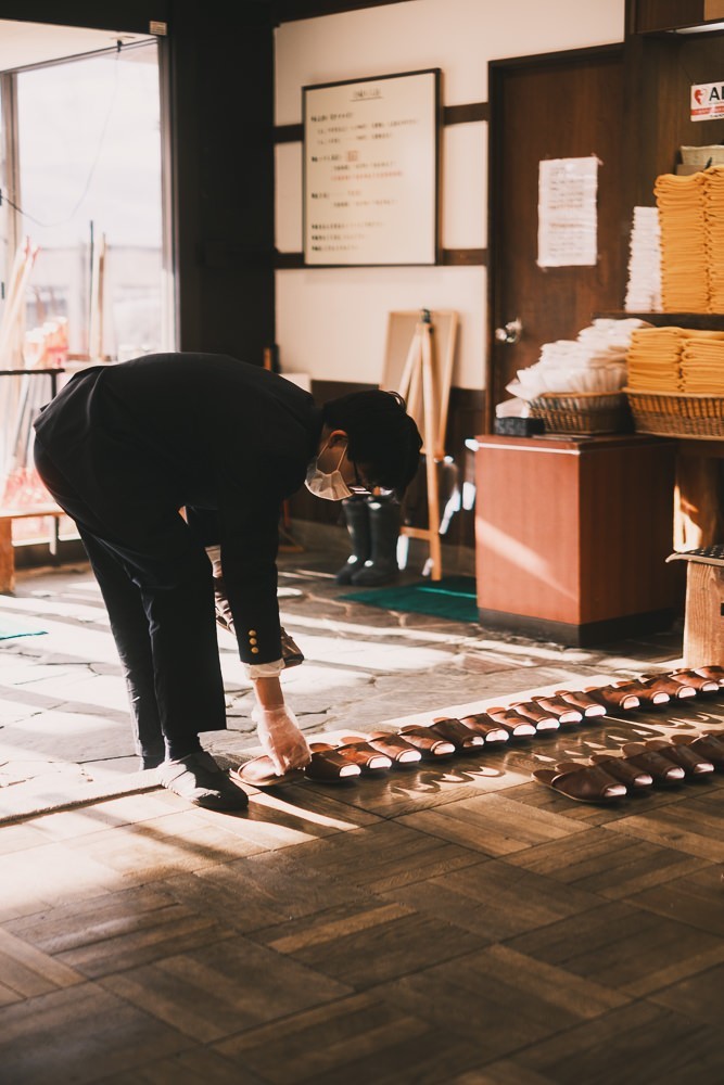 Japanese man organizing sandals at Sukayu Onsen