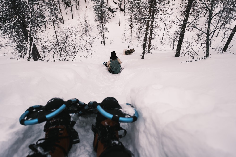 Glisading down snowy hill in Urho Kekkosen National Park