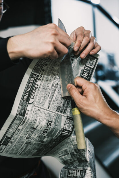 Testing sharpness of knife with newspaper cut test