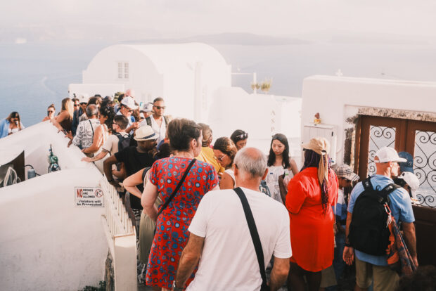 Large crowd of people waiting to take photo at special door in Oia