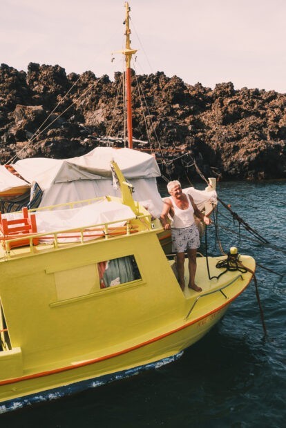 Local fisherman in yellow boat near Palea Kameni in Santorini