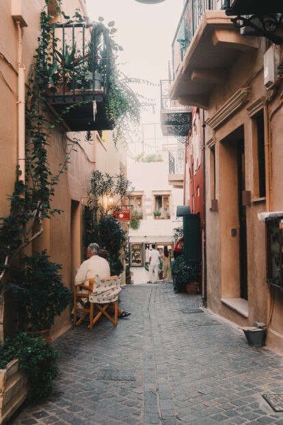 Small alleyway in Chania with two residents sitting on a chair outside