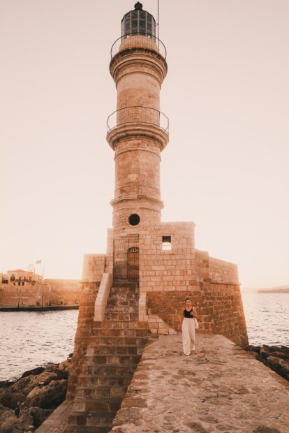 Girl walking away from Chania Old Harbor Lighthouse
