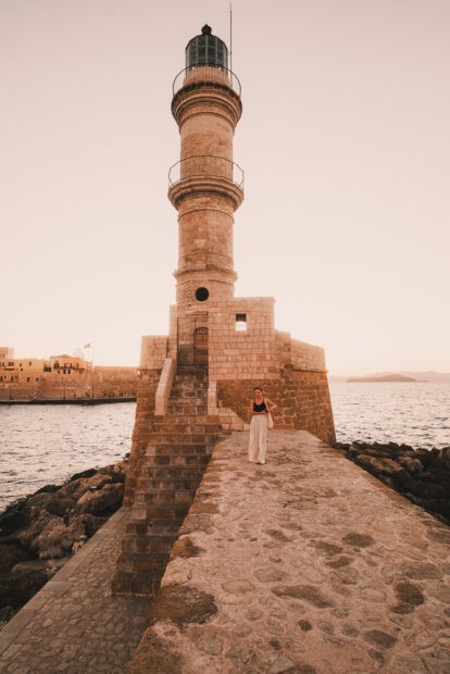 Girl standing in front of the Venetian Lighthouse in Chania at sunset