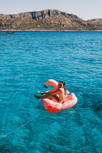 Girls sitting on giant pink flamingo float at Gramvousa Island