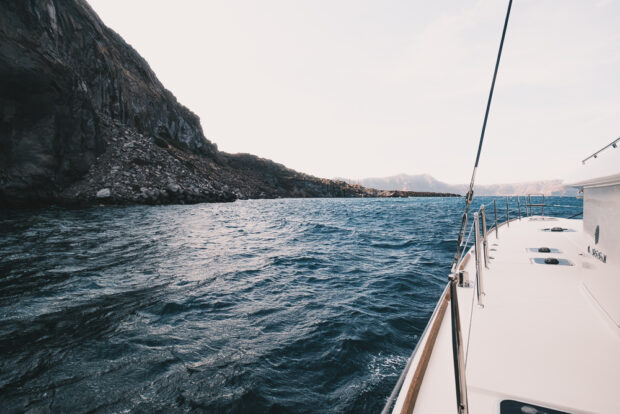 Catamaran passing by Volcanic rocks of Nea Kameni