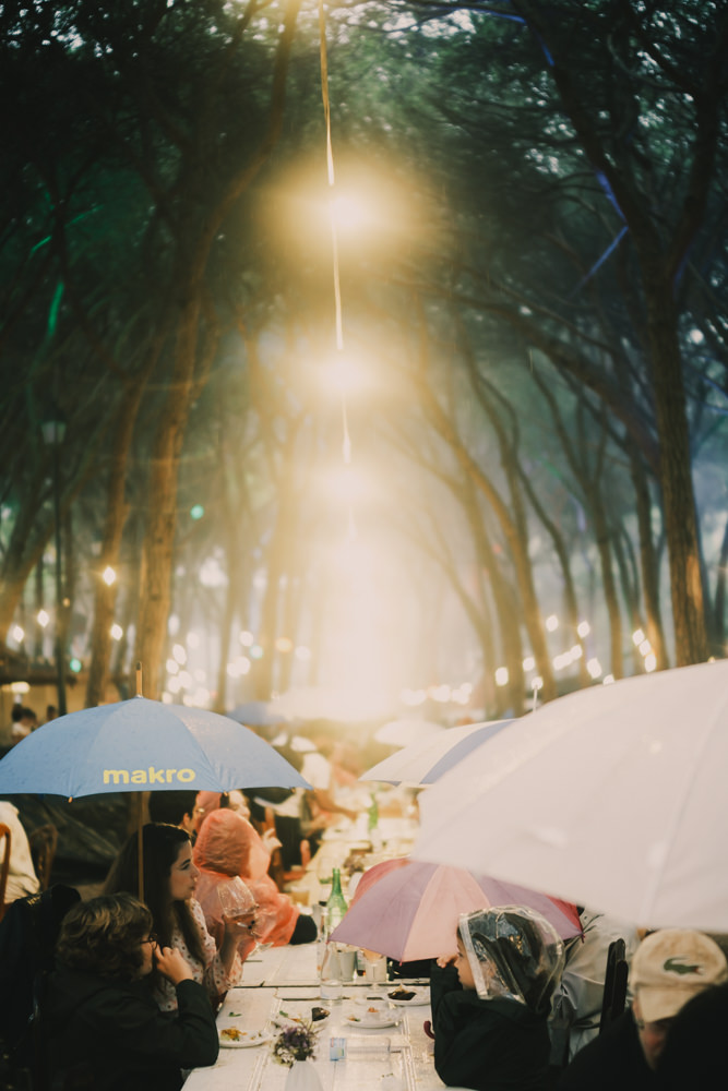 Umbrellas and rain at long communal table Chefs on Fire Cascais
