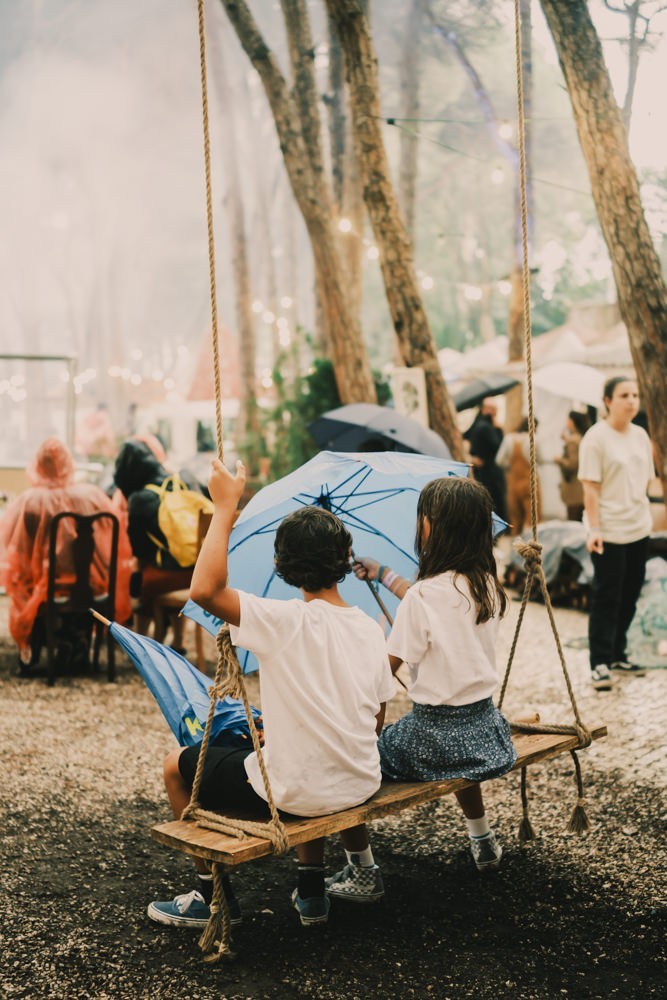 Two children sitting on wood swing with umbrella at Chefs on Fire Cascais